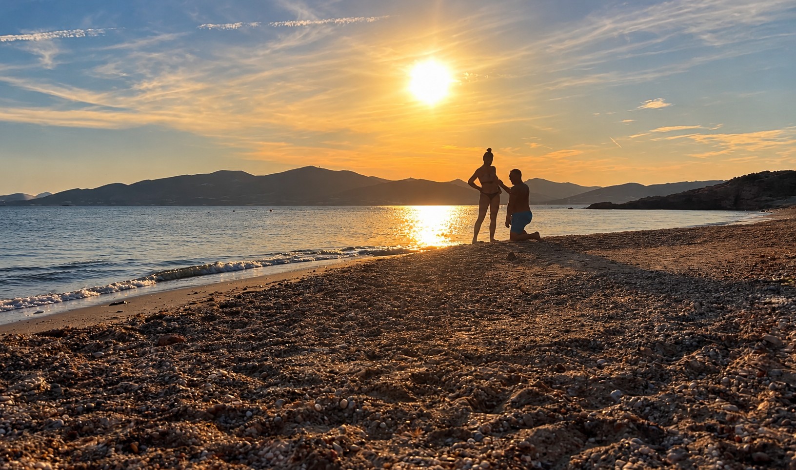 Pete Lawrence proposing to Lizi Sage on a beach at sunset in Paros